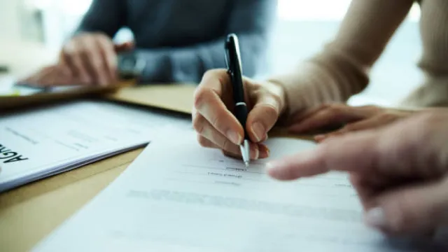 Fotografia de pessoas assinando um contrato.