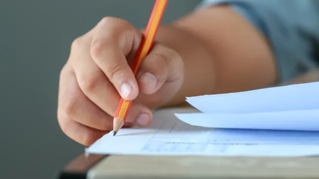 Foto de uma pessoa escrevendo no papel com um lápis
