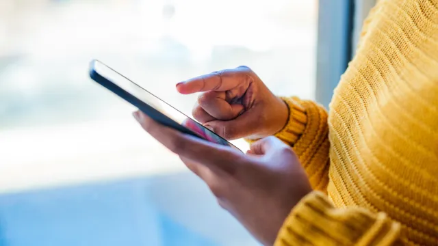 Fotografia focalisada nas mãos de uma mulher digitando no smartphone